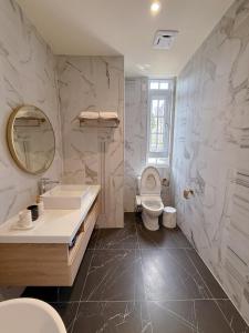 a bathroom with a toilet and a sink and a mirror at Station B&B in Tainan