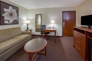 a hotel room with a couch and a table and a television at AmericInn by Wyndham Spencer in Spencer