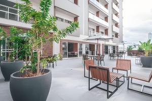 an outdoor patio with tables and chairs and plants at Estúdio Praga: Vista para o por do sol in Criciúma
