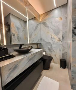 a bathroom with a sink and a marble wall at Estúdio Praga: Vista para o por do sol in Criciúma