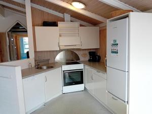 a white kitchen with a sink and a refrigerator at Holiday Home Eldmar - 500m from the sea by Interhome in Ålbæk