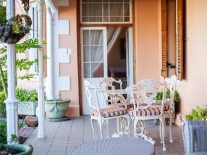 an outdoor patio with white chairs and a table at Connie’s Cottages in Montagu