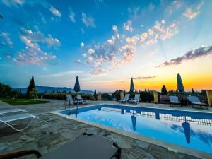 a pool with chairs and a sunset in the background at BOSCO VERDE Corfu Apartments in Gouvia