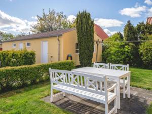 Una mesa blanca y bancos en un patio. en Apartment Annbritt - 500m from the sea by Interhome, en Skagen