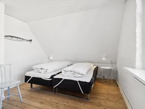 a bed in a room with white walls and wooden floors at Holiday Home Ortrud - 200m from the sea by Interhome in Skagen +19 photos