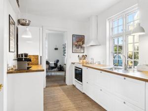 a white kitchen with white cabinets and a sink at Holiday Home Ortrud - 200m from the sea by Interhome in Skagen