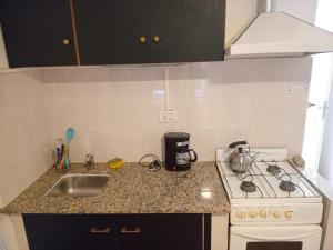 a kitchen counter with a stove and a sink at Departamentos Perla del mar in Las Grutas