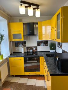 eine Küche mit gelben Schränken und schwarzen Arbeitsplatten in der Unterkunft Стильна та затишна однокімнатна квартира на бульварі Шевченка с кондиціонером,поруч парковка з охороною in Tscherkassy