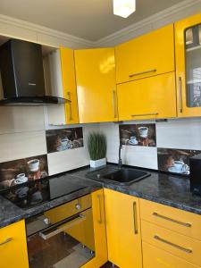 eine Küche mit gelben Schränken und einem Waschbecken in der Unterkunft Стильна та затишна однокімнатна квартира на бульварі Шевченка с кондиціонером,поруч парковка з охороною in Tscherkassy + 2 Fotos