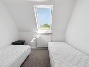 Un dormitorio blanco con dos camas y una ventana. en Apartment Angelie - 350m from the sea by Interhome, en Neksø