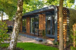 una casa con pareti in vetro e una terrazza in legno di De Leughte Resort Renswoude a Renswoude