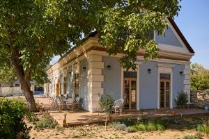 a white house with chairs and a tree at Icce Borbirtok - Wine, Dine & Rest in Monoszló