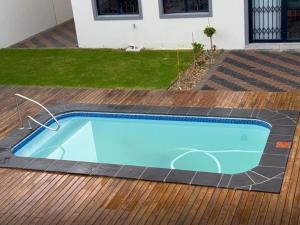 una piscina azul en una terraza de madera en Bokwe Guesthouse - Gordons Bay, en Gordonʼs Bay