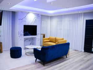 Una sala de estar con un sofá azul y un televisor. en Bokwe Guesthouse - Gordons Bay, en Gordonʼs Bay