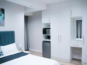 1 dormitorio con armarios blancos y 1 cama en Bokwe Guesthouse - Gordons Bay, en Gordonʼs Bay