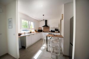 una cucina con mobili bianchi, un tavolo e sgabelli di Villa Bulle Dorée & Spa privatif Amnéville ad Amnéville