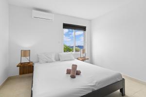 a bedroom with a white bed and a window at Playa Breeze Apartment in Kralendijk +21 photos