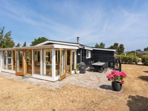 a small black and white house with a patio at Holiday Home Sari - 250m from the sea by Interhome in Sønderby