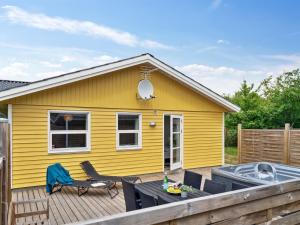 a yellow house with a wooden deck with a table at Holiday Home Barth - 950m from the sea by Interhome in Vig