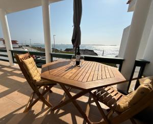 a wooden table and chairs on a balcony with the ocean at Pura Vida Baleal in Baleal