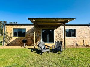 two chairs and a table in front of a house at Apple Cottage in Grabouw