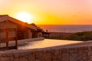 a sunset over the ocean and a house with a wall at Villa Vittoria - Costa Paradiso in Costa Paradiso