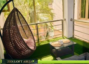 a hammock on a balcony with a table and a window at Zen Loft Terrace Maitama Abuja in Abuja