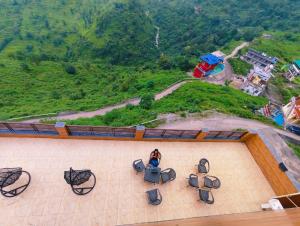 a woman sitting on a patio with chairs and a mountain at Sach Naina Residency, Mussoorie in Jāmb
