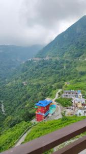 a building with a blue roof next to a mountain at Sach Naina Residency, Mussoorie in Jāmb