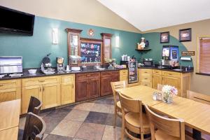 a kitchen with wooden cabinets and a table and chairs at AmericInn by Wyndham Sheboygan in Sheboygan