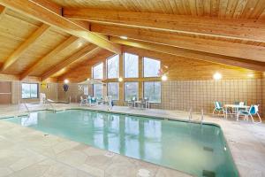 a swimming pool in a room with a table and chairs at AmericInn by Wyndham Sheboygan in Sheboygan