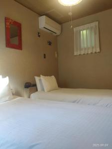 zwei Betten in einem Hotelzimmer mit weißen Laken in der Unterkunft ファミーユグループ城ケ崎店 海音Umine in Ito