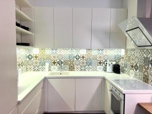 een keuken met witte kasten en een tegelmuur bij Vilnius Apartments & Suites – Old Town in Vilnius