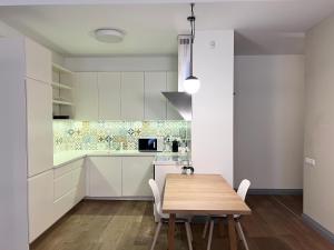 een keuken met witte kasten en een houten tafel bij Vilnius Apartments & Suites – Old Town in Vilnius