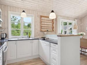 a kitchen with white cabinets and two windows at Holiday Home Tia - 1-4km from the sea by Interhome in Sæby