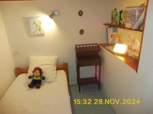 ein kleines Schlafzimmer mit einem Teddybär, der auf einem Bett sitzt in der Unterkunft Les Alizes in Le Grau-dʼAgde + 2 Fotos