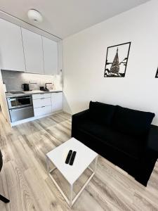 ブラチスラヴァにあるApartmán na NFŠ Bratislavaのリビングルーム(黒いソファ、白いテーブル付)