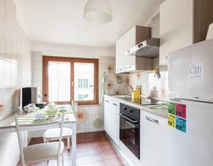 a white kitchen with a table and a stove top oven at Lakeview loft in Rivoltella
