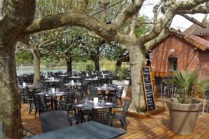 a restaurant with tables and chairs on a wooden deck at Le Toué, Charme and Voie Bleue 