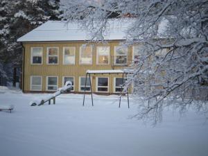 uma casa na neve com um parque infantil em Gafsele Lappland Hostel em Väster Gafsele