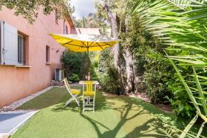 a patio with a table and a yellow umbrella at Chambre avec entrée indépendante-Jardin privé- 200m des plages in Théoule-sur-Mer