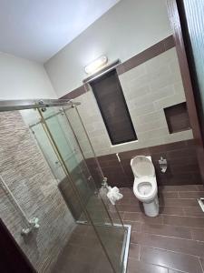 a bathroom with a toilet and a glass shower stall at Tribal house in Karachi