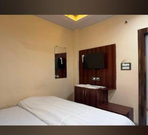 ウッジャインにあるHotelShreesanwariyapalaceの白いベッドとテレビのある寝室