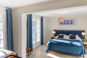 a bedroom with a blue bed with blue curtains at Family Home in the Heart of the Luberon with Swimming Pool and Panoramic Vi in Mérindol +24 photos