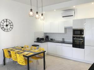 a kitchen with a dining table and yellow chairs at Appartement Lumea 80 m2 climatisé parking proche Sanctuaires in Lourdes