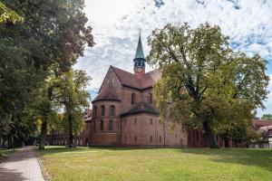 a large brick building with a steeple on a grass field at Tiny House Evita in Nahmitz