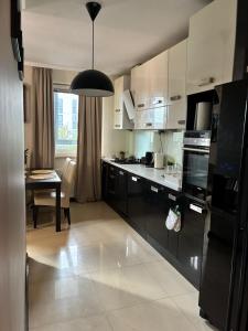 a kitchen with white cabinets and a black refrigerator at Deluxe Apartament na wyłączność z darmowym parkingiem w garażu fv in Warsaw