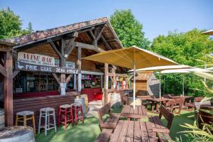 a restaurant with wooden tables and chairs and an umbrella at Camping Mobil Home 6 Pers Rivage des Landes Piscine Landes in Aureilhan