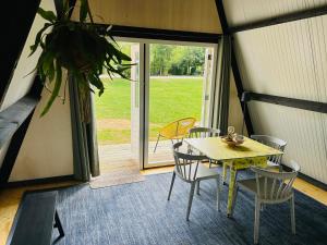 a table and chairs in a room with a door at Tiny House 'The Cabin' in Berlicum