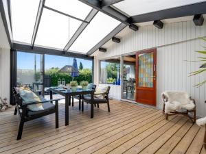 a conservatory with a table and chairs on a wooden deck at Holiday Home Keke - 120m from the sea by Interhome in Rødvig